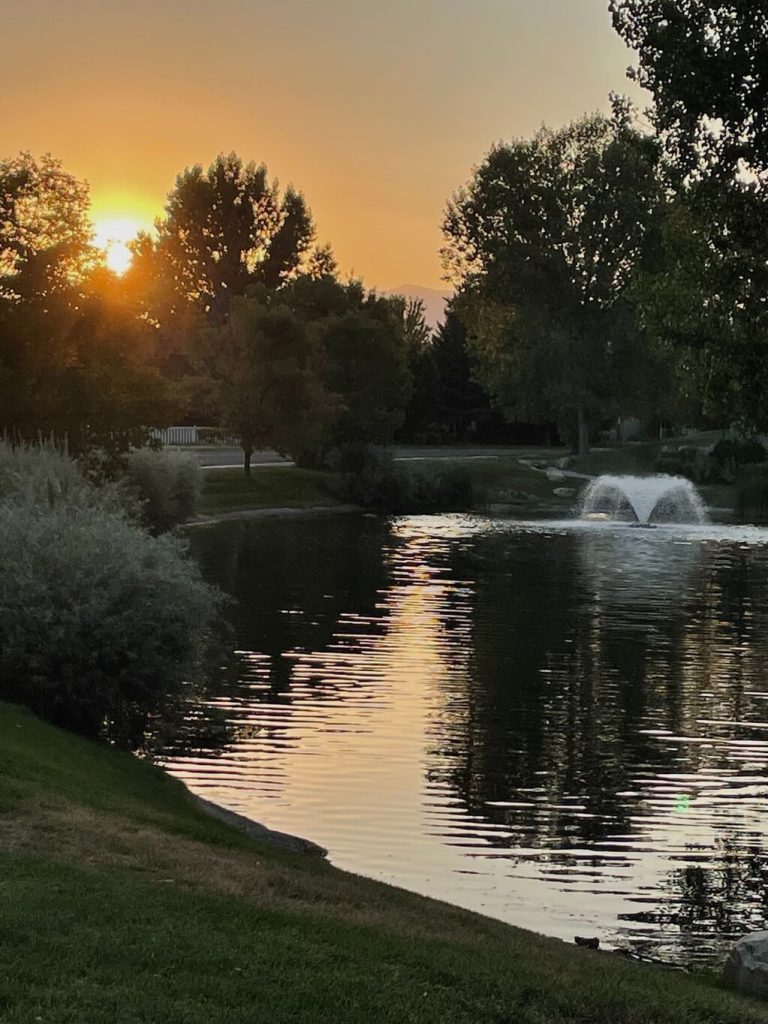 A sunset over a pond with a fountain