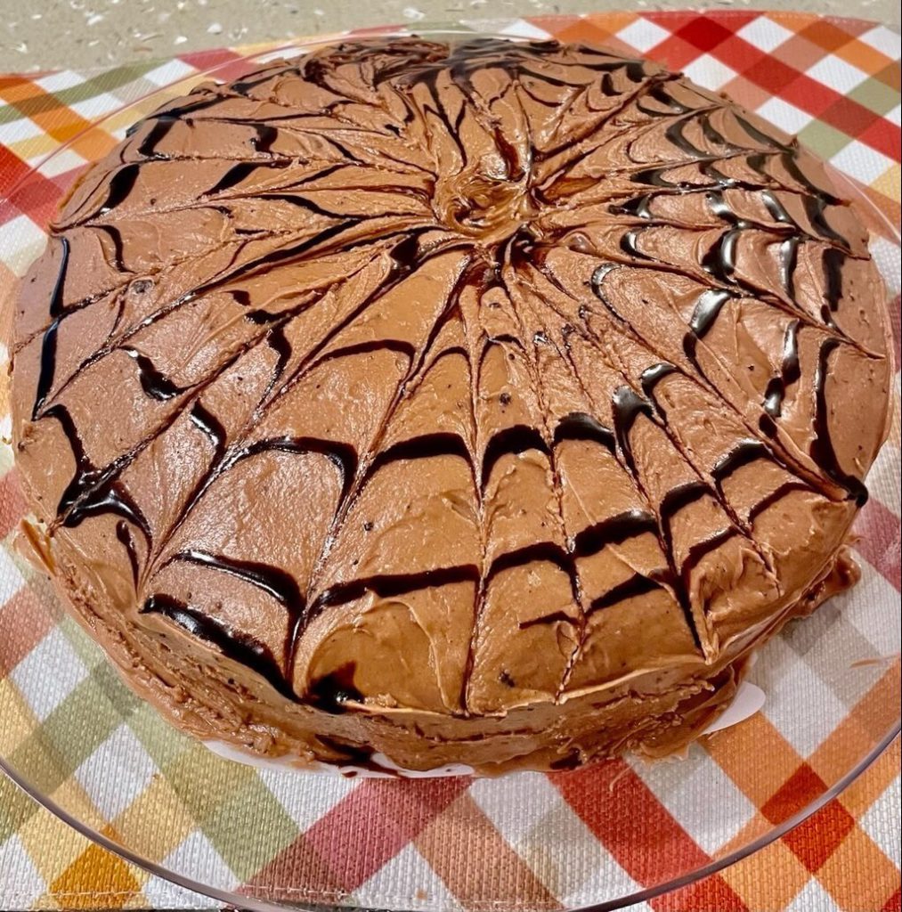 A chocolate cake with a spiderweb design on top