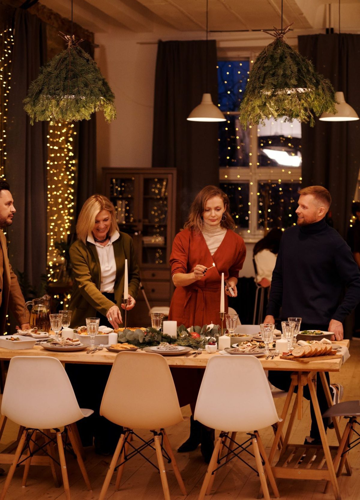 2 men and 2 women setting up a dinner table with candles