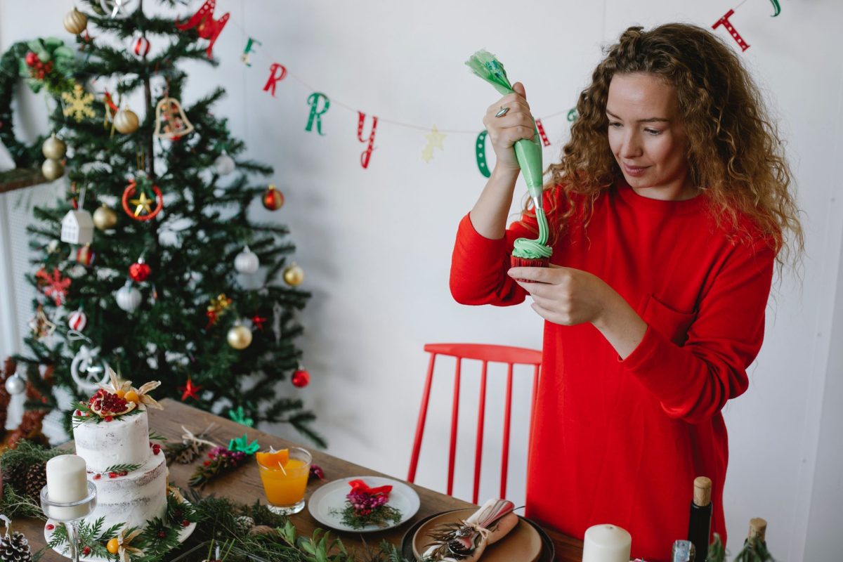 comfortable home cooking woman in red putting icing on a cupcake