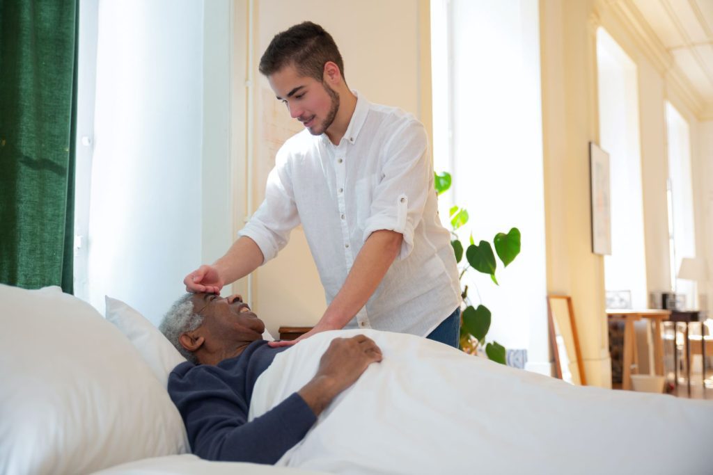 Choosing In-Home Caregiver young man checking on an old man's temperature