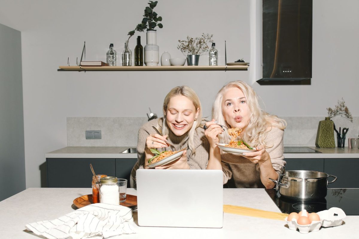 two ladies eating food in front of a laptop