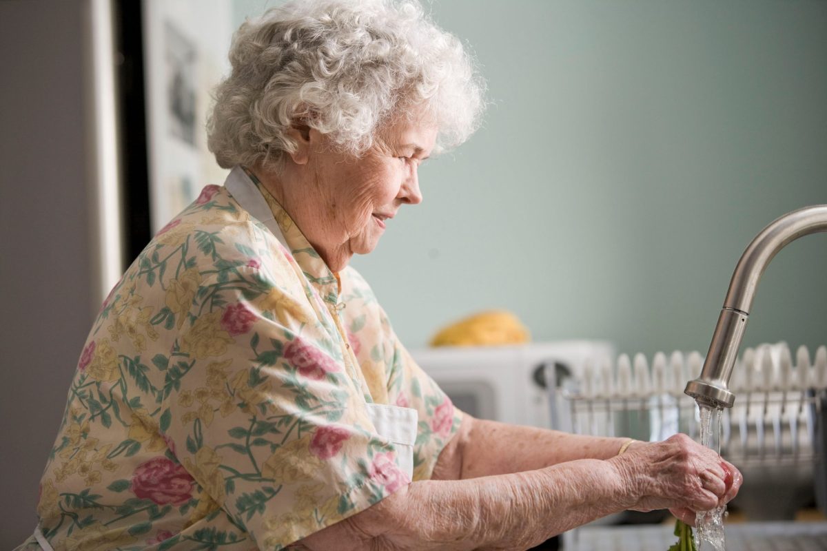 An old woman washing her hands, ensuring safety in family caregiving.