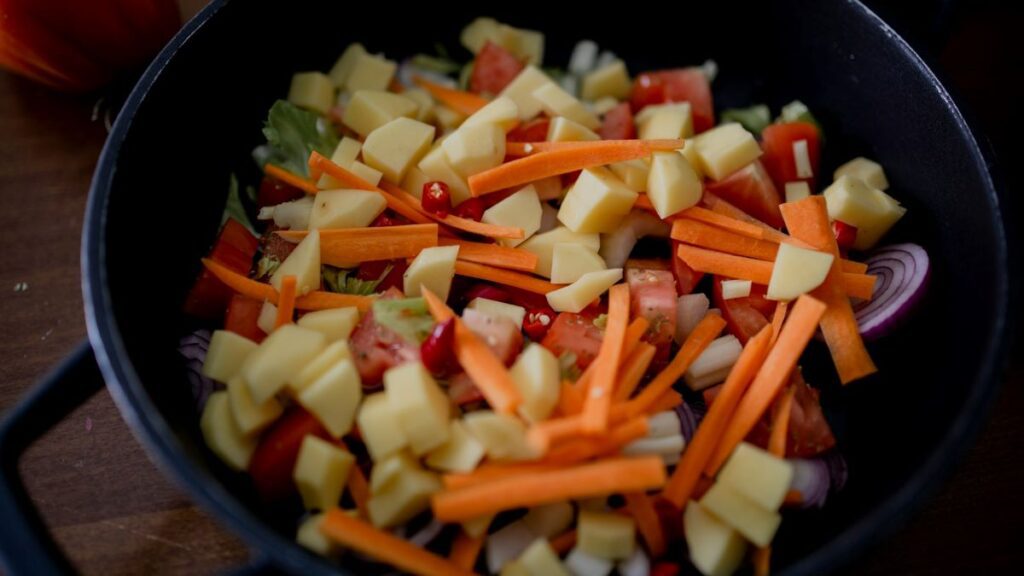 image of a bowl of chilis, carrots, potatoes, onions, and cabbages showing the final product of following these tips on making tasty and healthy food