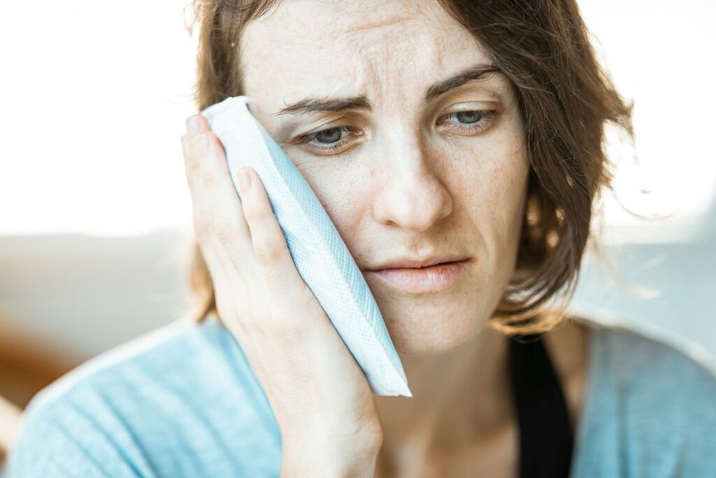 image of woman holding ice pack on her cheek as she utilizes a caregiver pain management plan