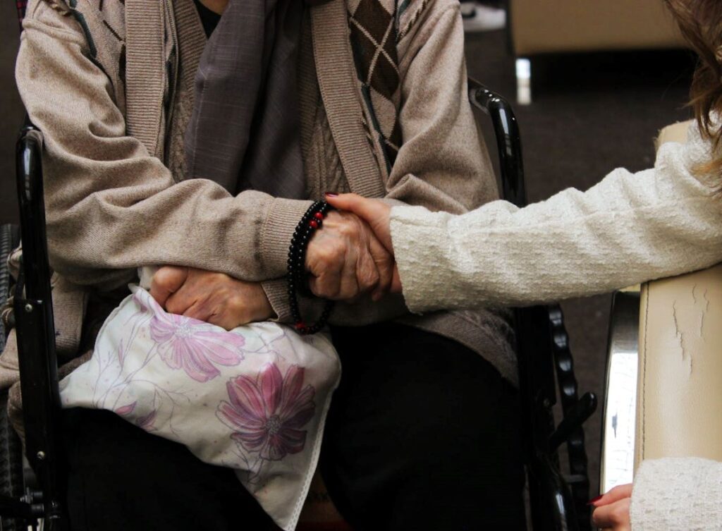 a woman holding the hand of an elderly person, understanding caregiving resentment