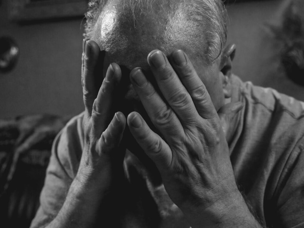 A man covering his face as a manifestation of resentment