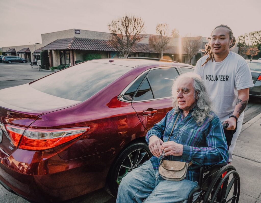 A man assisting an elderly in the wheelchair. Coping with caregiver worries can be done by having breaks and strolling around for fresh air.