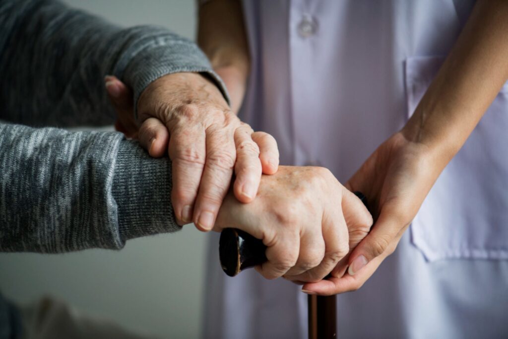 a photo of a caregiver holding an elderly’s hand showing the cognitive benefits of caregiving
