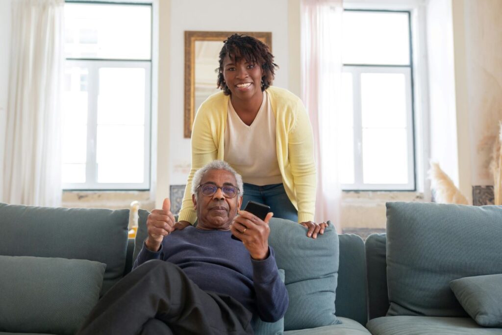 Caregiver and care recipient smiling at the couch, depicting the surprising health benefits of family caregiving