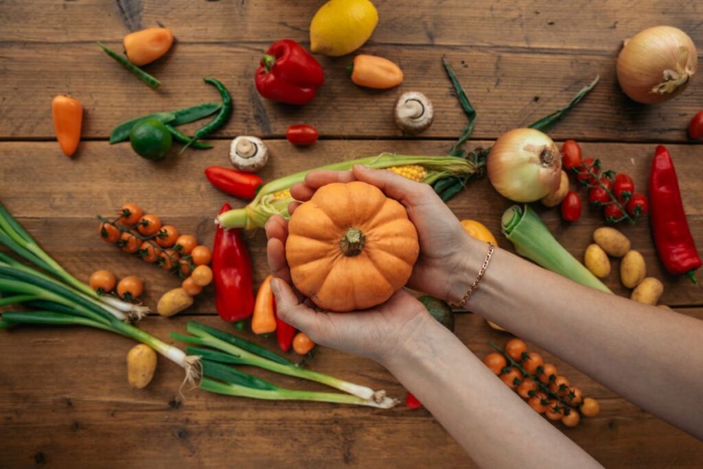 Photo of a person holding a vegetable with vegetables scattered in the background, a depiction of managing nutrient deficiencies.