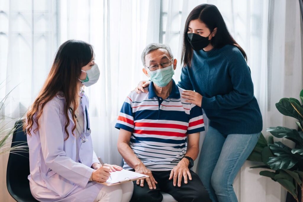 A caregiver and her care receiver talking to the doctor, depicting what doctor visits as a caregiver are like.