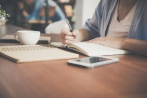 A person writing on her notebook, embodying resilience through caregiver journaling.