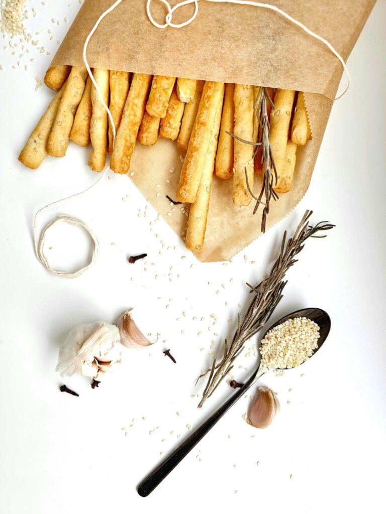 A bag of breadsticks alongside a spoon, representing classic bread recipes and culinary preparation.