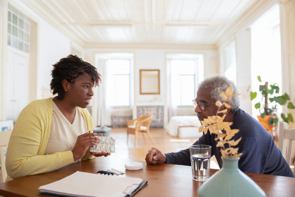 A woman and an older man sit at a table, engaged in a conversation about how to coordinate care.