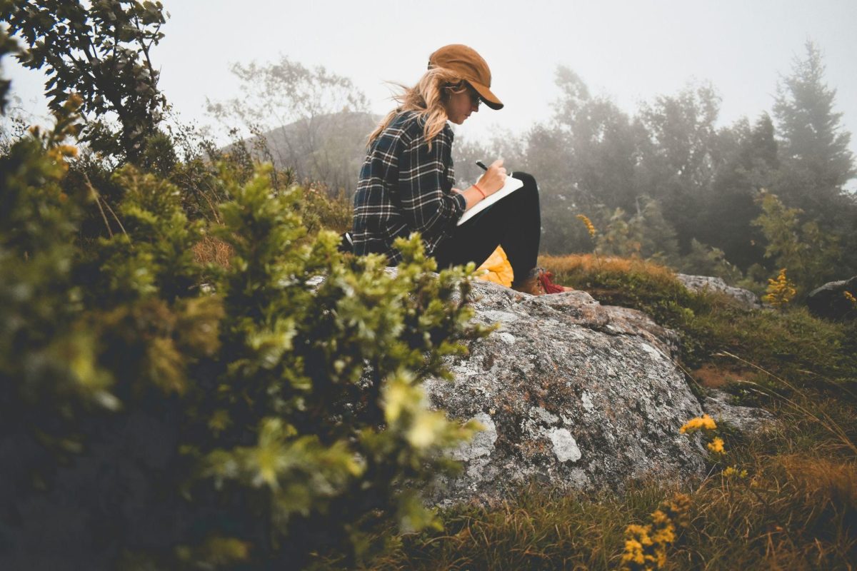 A person writing on her journal, utilising daily journaling prompts for caregivers.