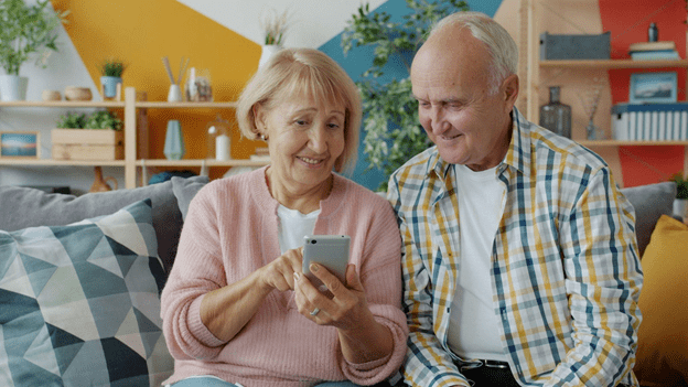 The elderly woman showing the elderly man her phone.
