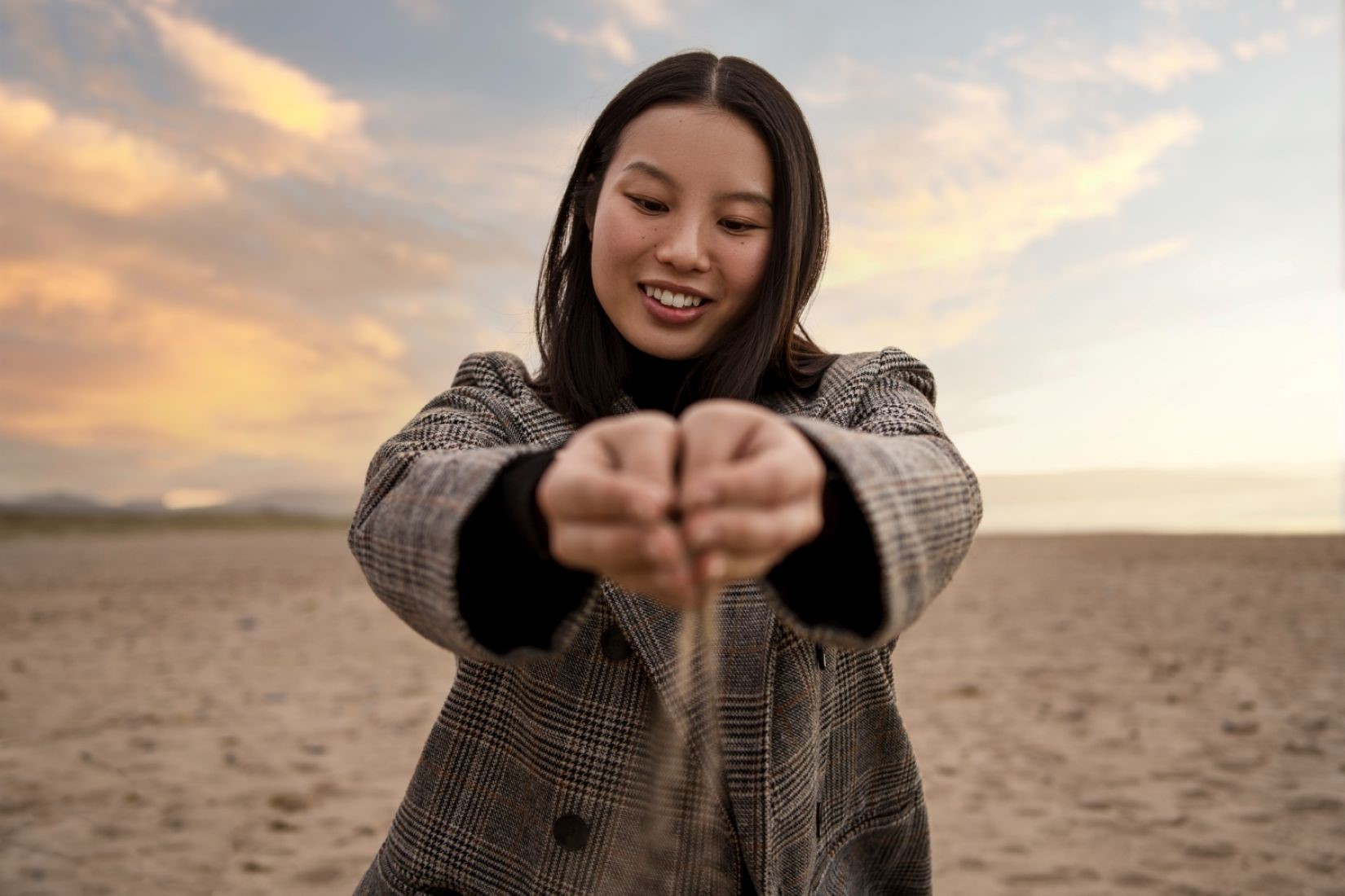 A woman letting sand fall through her hands.