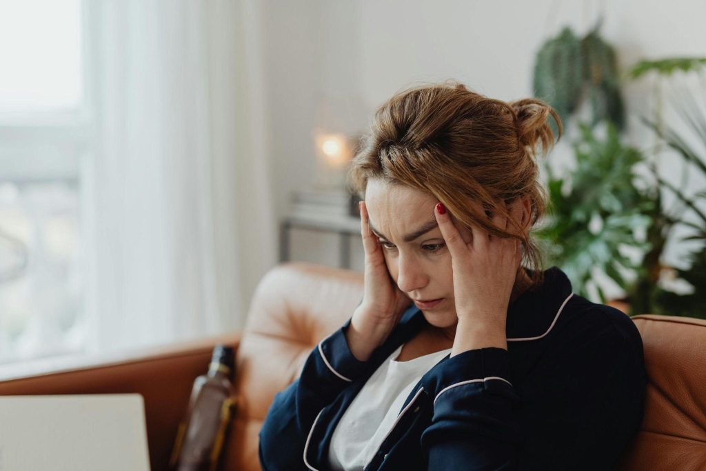 Woman with her hands on her temples, looking stressed, showcasing how sleep deprivation impacts family caregivers’ health.