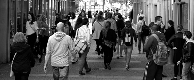 A street scene shows a diverse crowd of pedestrians walking in both directions.