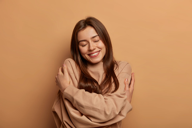 A woman embracing herself in self-care.