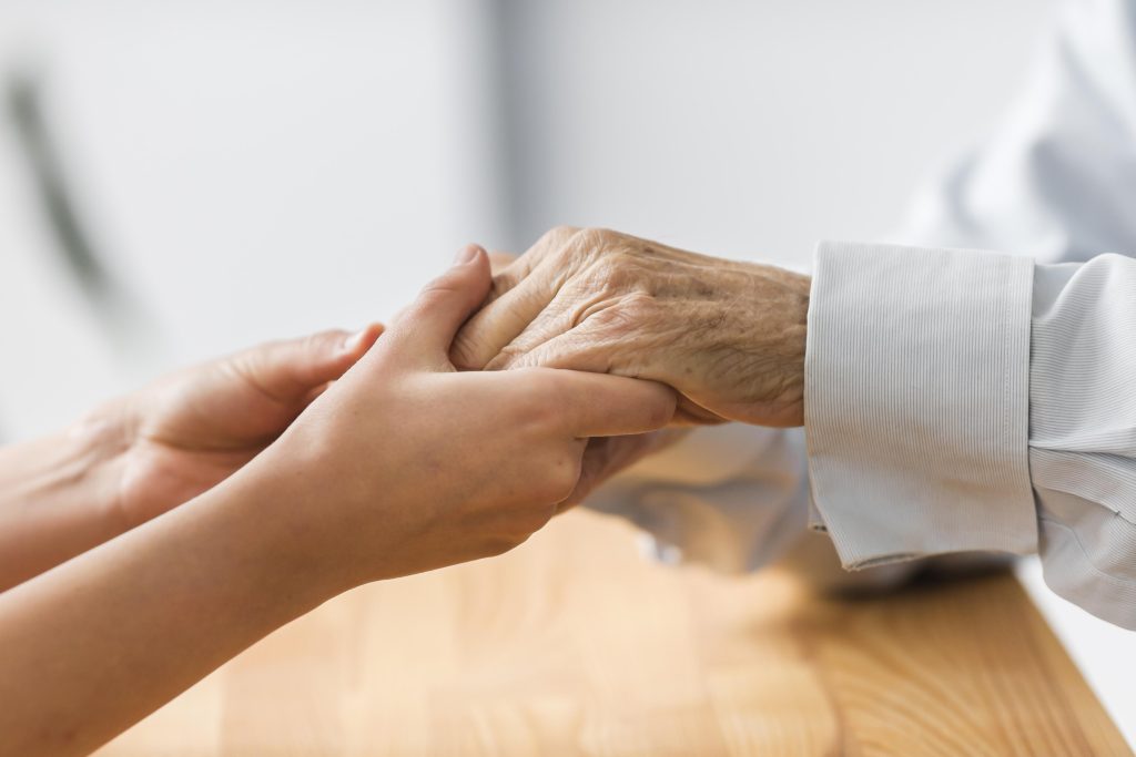 A young woman holding a senior's hand | Image Source: Freepik