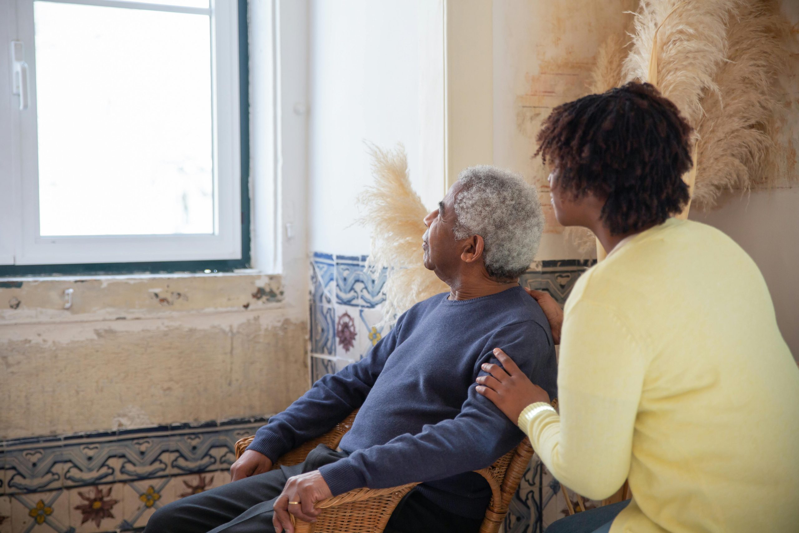 A woman assisting an elderly man | Image Source: Pexels