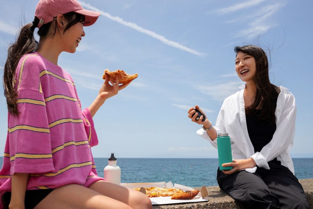 Two people eating by the sea.