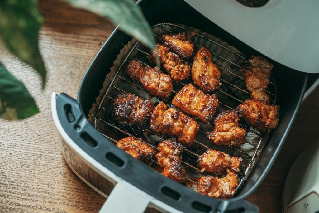 Grilled chicken pieces in an air fryer basket, showing a crispy, golden-brown texture, countering chicken cooking mistakes.