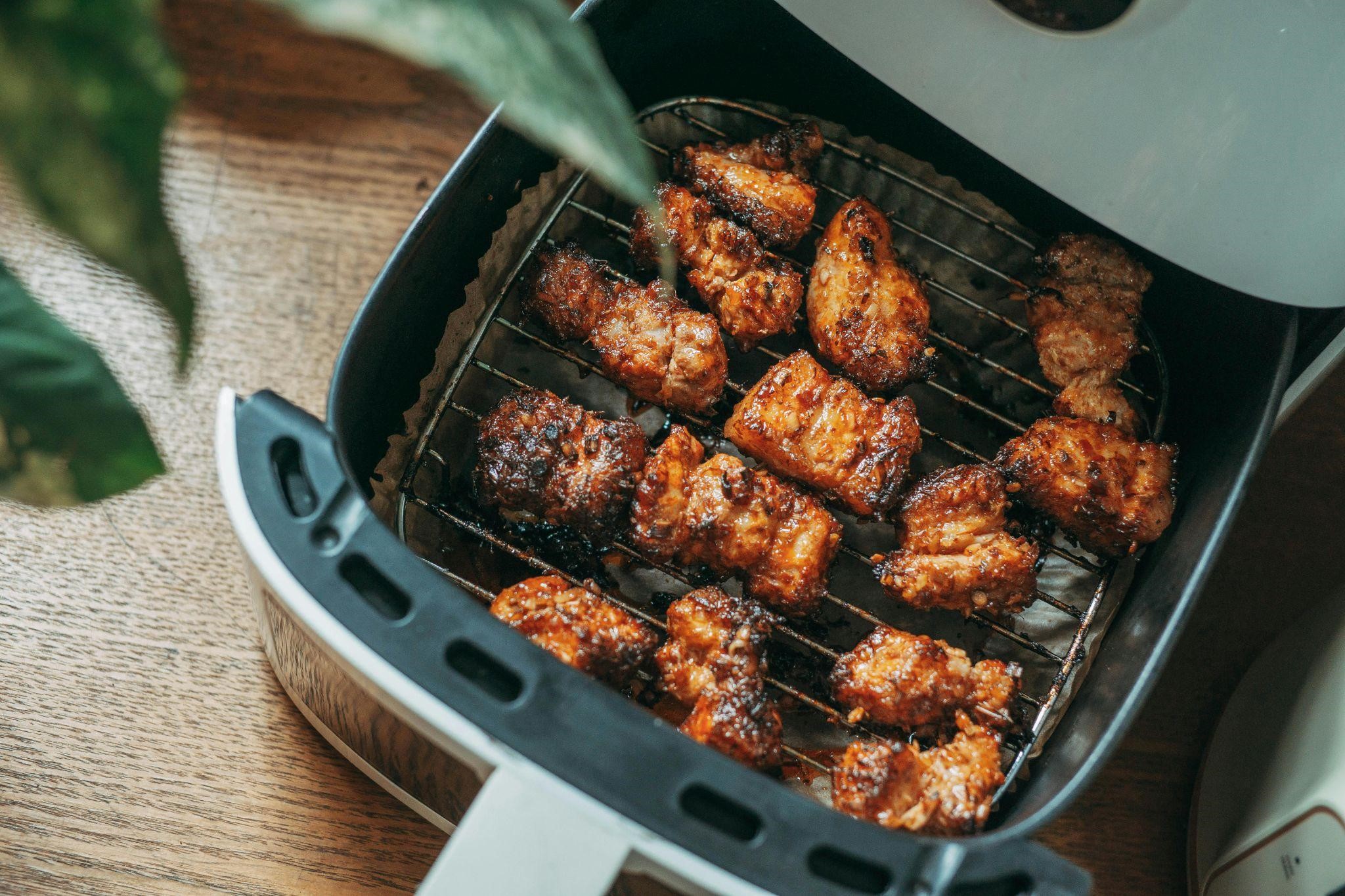 Grilled chicken pieces in an air fryer basket, showing a crispy, golden-brown texture, countering chicken cooking mistakes.
