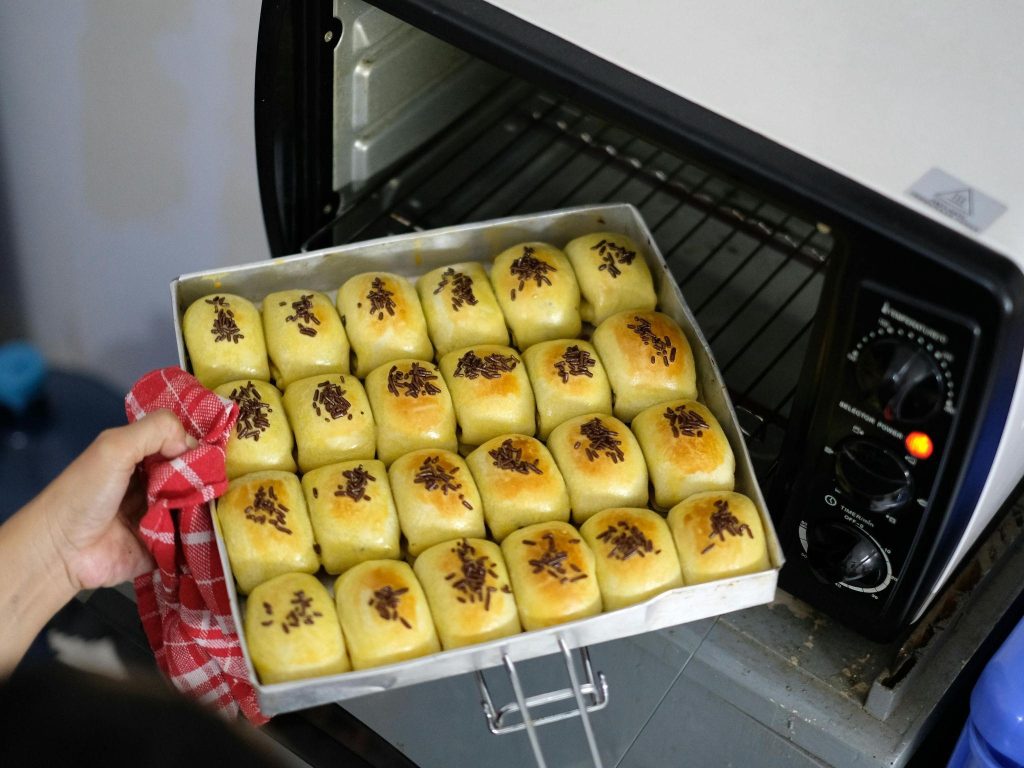 A person pulls out a tray of freshly baked pastries from an oven, avoiding the common baking mistakes.