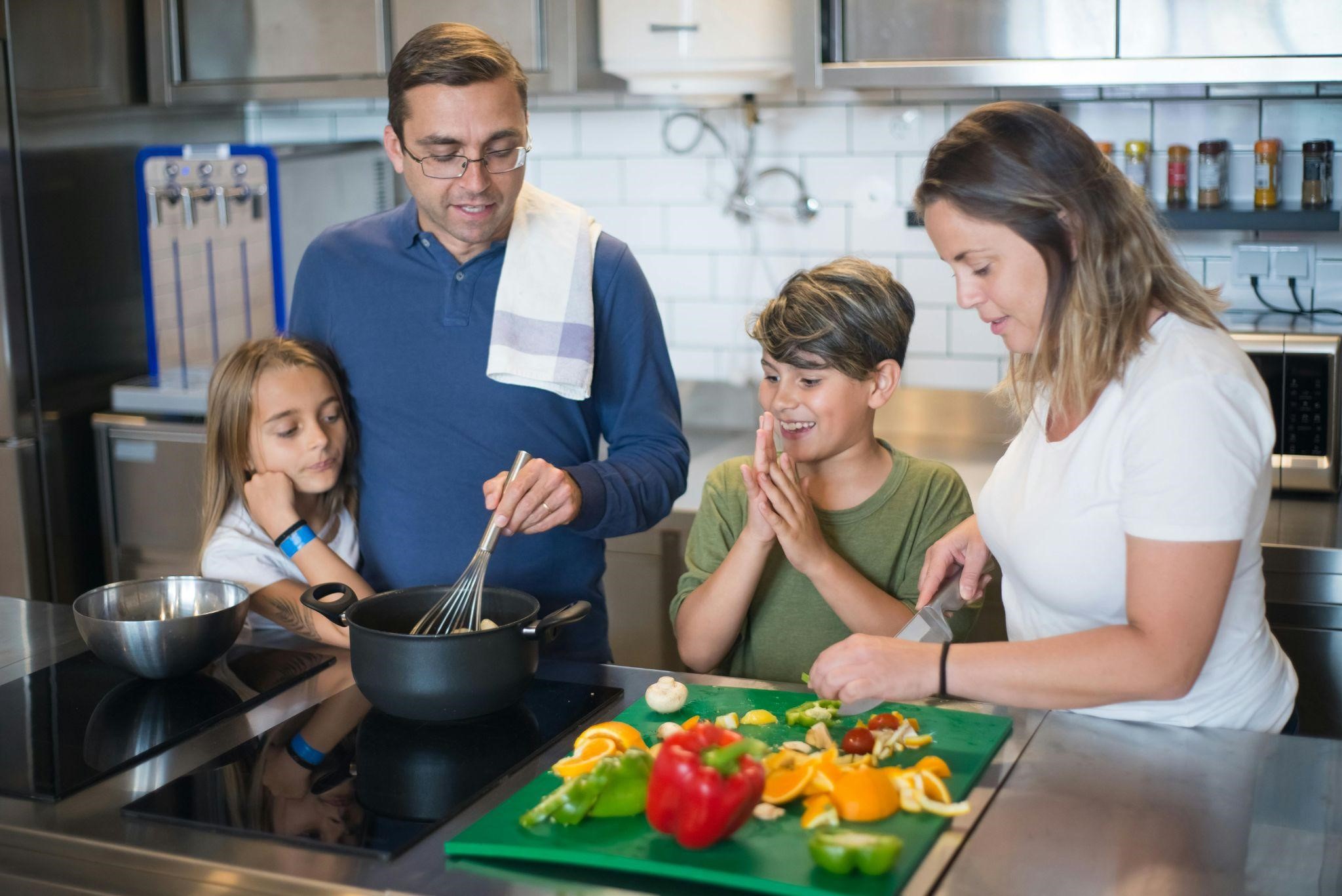 A family of four cooks together in a modern kitchen, utilizing easy dinner ideas.