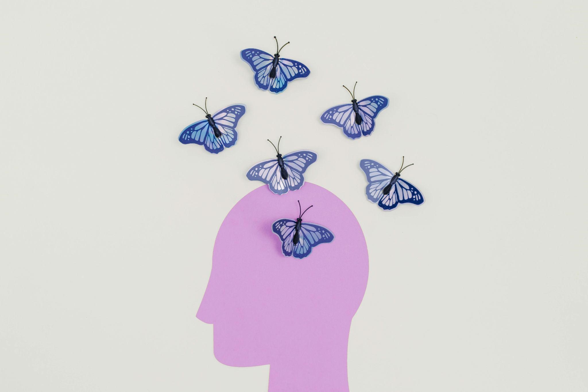 Silhouette of a purple human head with butterflies above it, symbolizing how symbols help promote dementia advocacy.