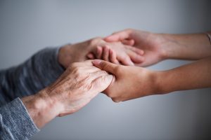 A woman holding hands with an elderly