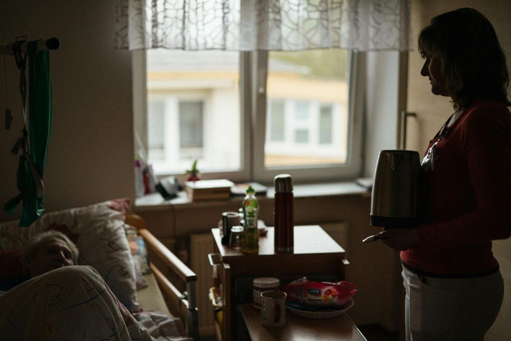 A caregiver stands in a dimly lit room, symbolizing what happens when caregivers reach the burnout stage.