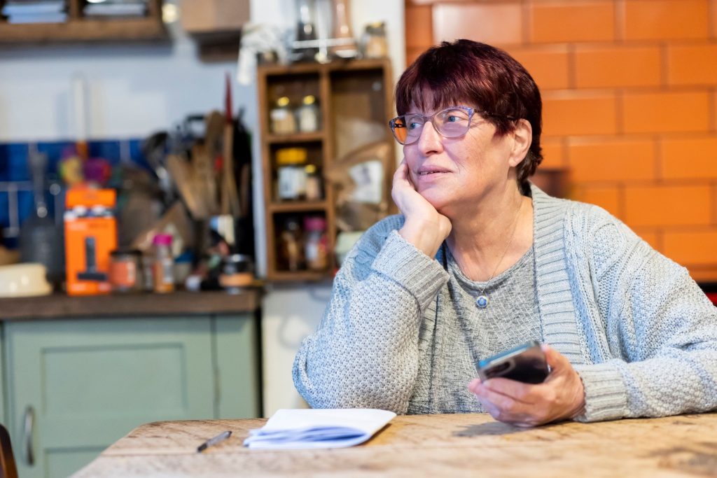 Family caregiver reviewing notes and phone while reflecting on the rights family caregivers have.