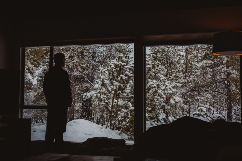 A man looking out and watching snow.
