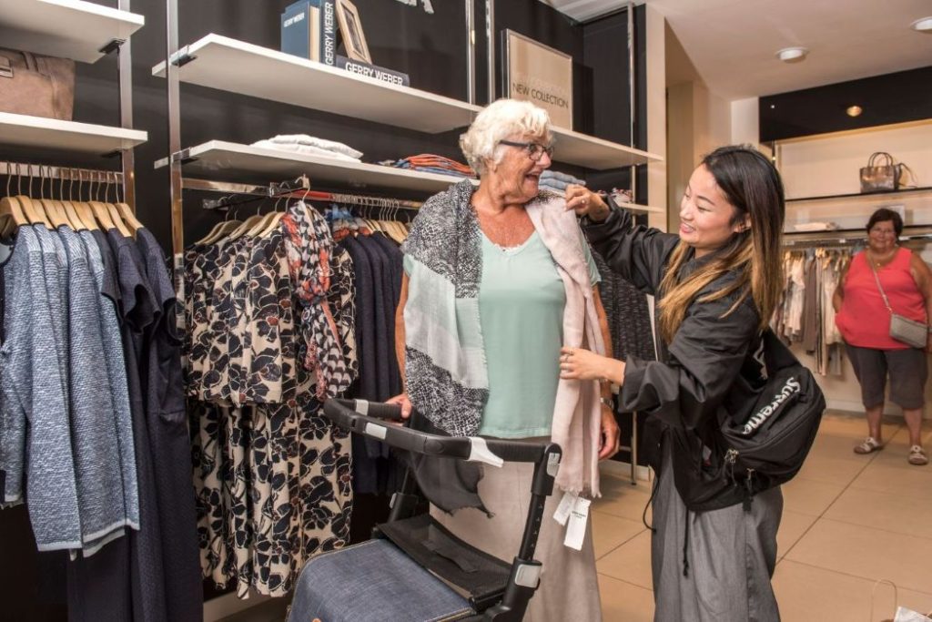 A caregiver buying clothes with her charge.
