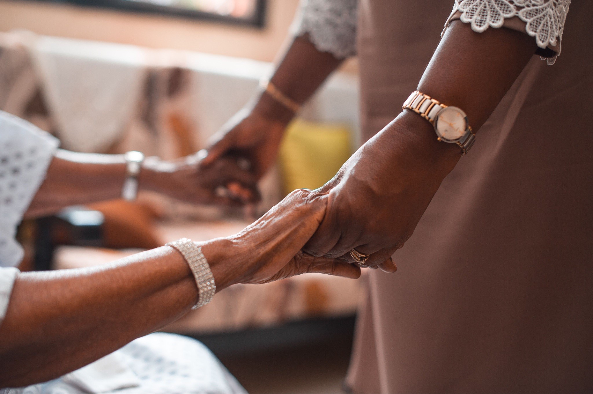 An elderly woman and her caregiver clasp hands, symbolizing the essence of hospice vs palliative care.