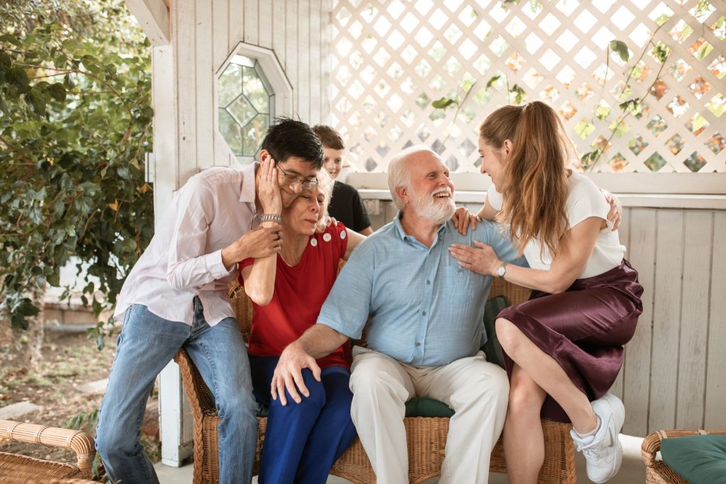 A family gathered on a porch, engaging with an elderly man, emphasizing family roles in dementia care.