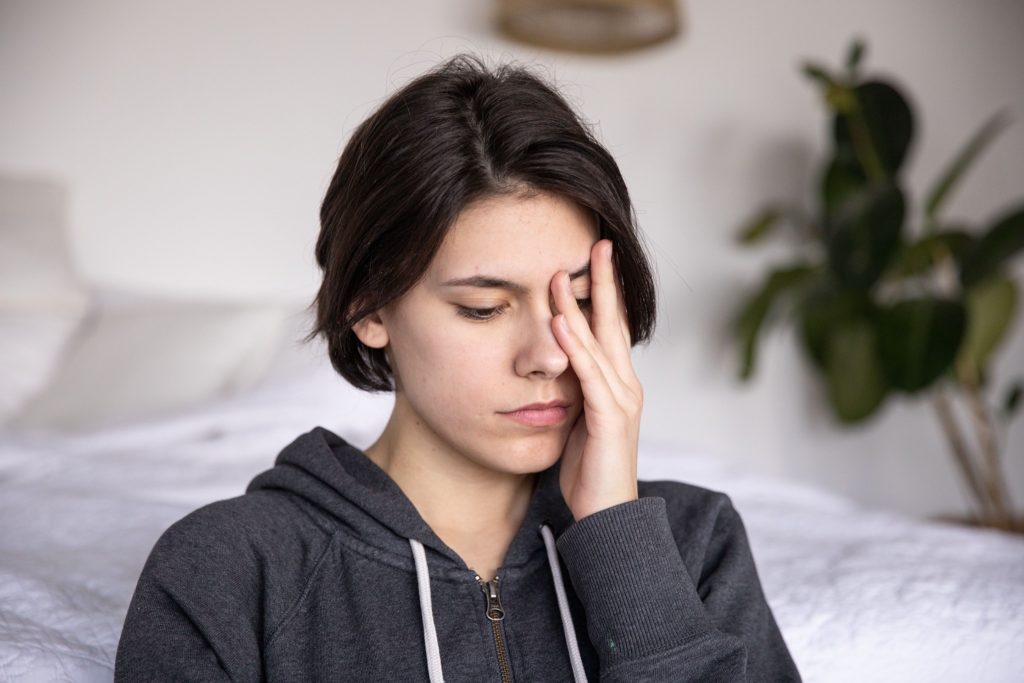 A woman covers her face with her hands, expressing why caregiving is emotionally demanding.