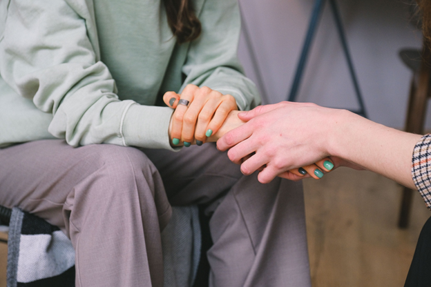 A woman gently holds the hand of another woman, symbolizing support and encouragement.